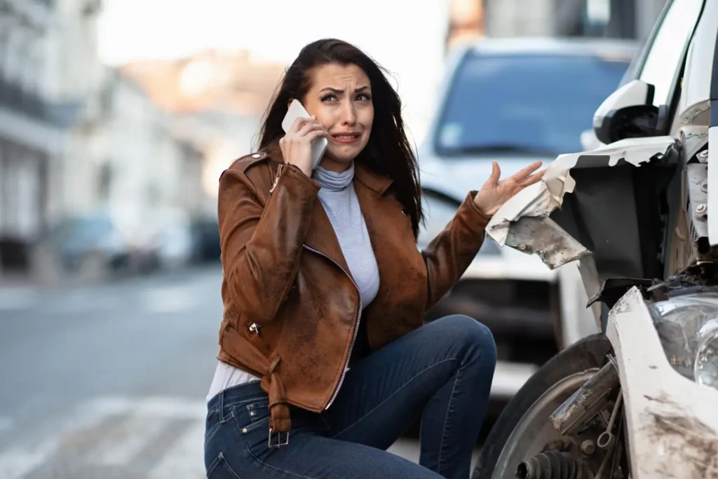 chica revisando su coche por choque por detras con otro coche